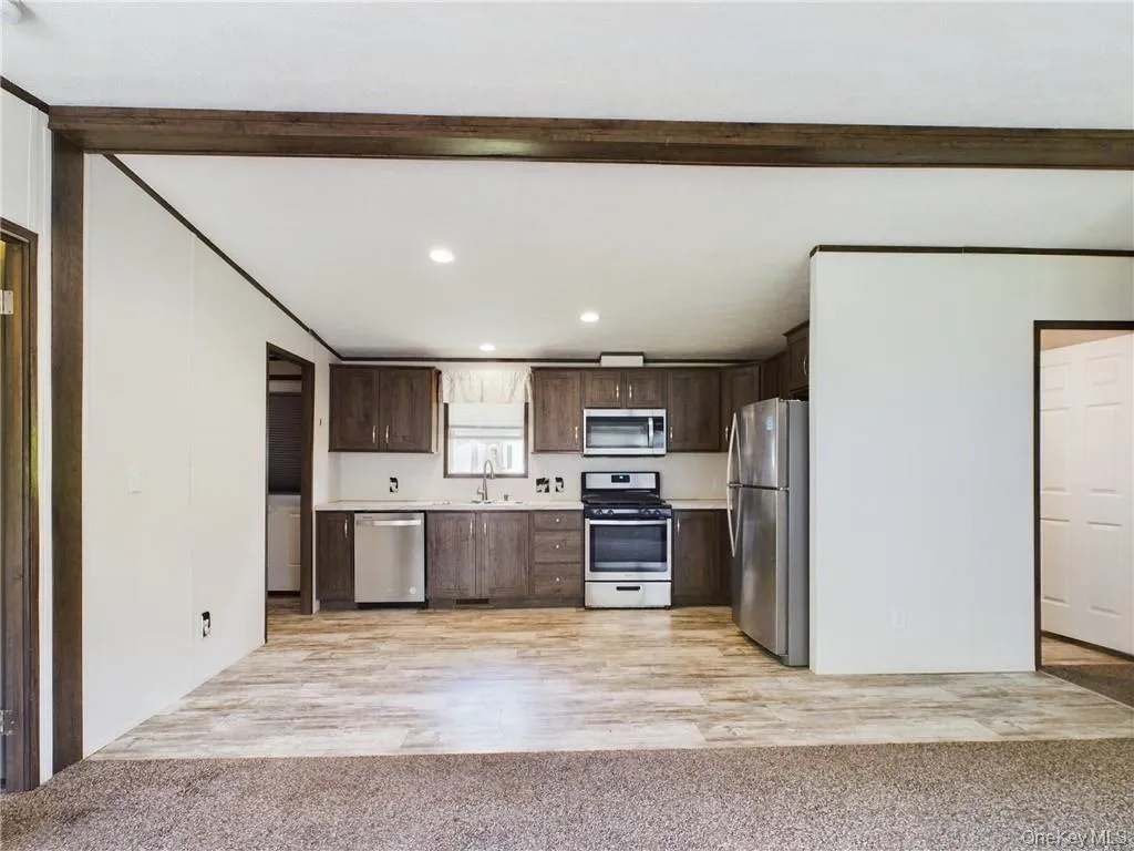 Kitchen featuring sink, light wood-type flooring, dark brown cabinetry, and stainless steel appliances Kitchen featuring sink, light wood-type flooring, dark brown cabinetry, and stainless steel appliances