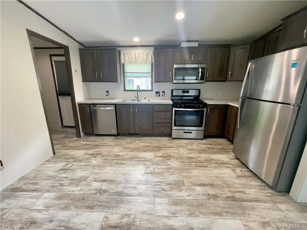 Kitchen with dark brown cabinets, sink, washer / dryer, and appliances with stainless steel finishes Kitchen with dark brown cabinets, sink, washer / dryer, and appliances with stainless steel finishes