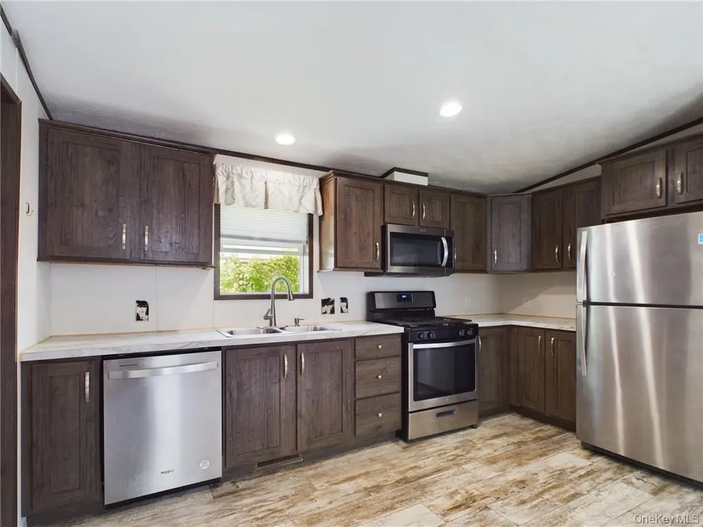 Kitchen with appliances with stainless steel finishes, light hardwood / wood-style floors, and dark brown cabinetry Kitchen with appliances with stainless steel finishes, light hardwood / wood-style floors, and dark brown cabinetry