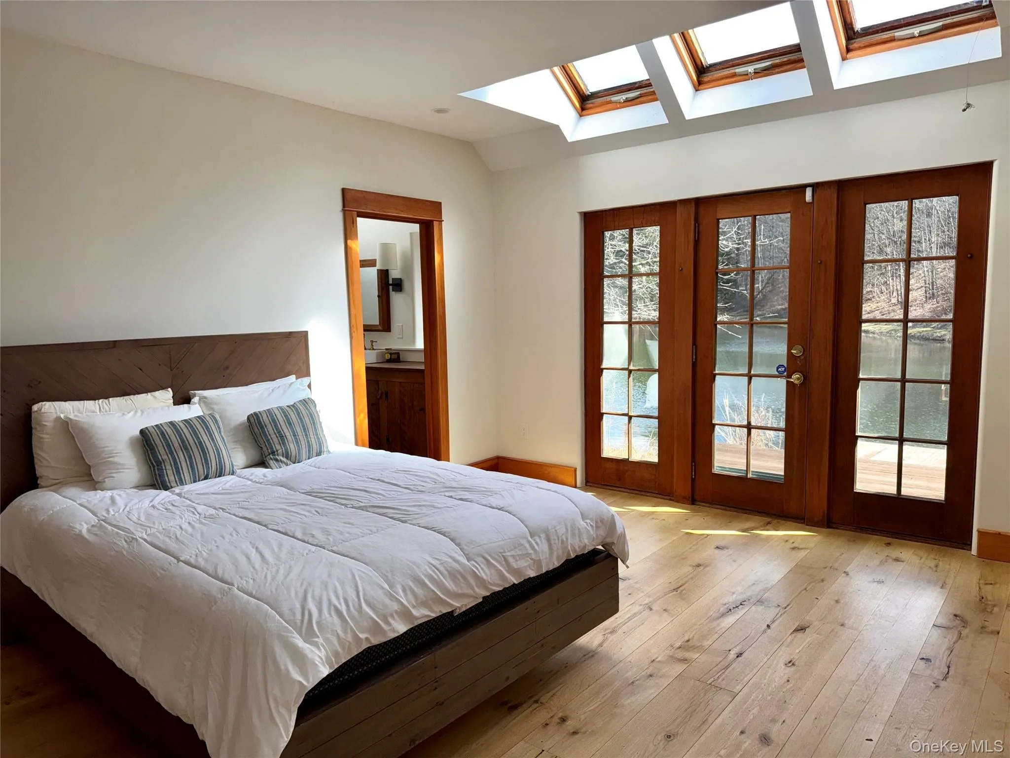 Primary Bedroom with Pine Floors, Vaulted Ceiling, Skylights & Screened Porch Primary Bedroom with Pine Floors, Vaulted Ceiling, Skylights & Screened Porch