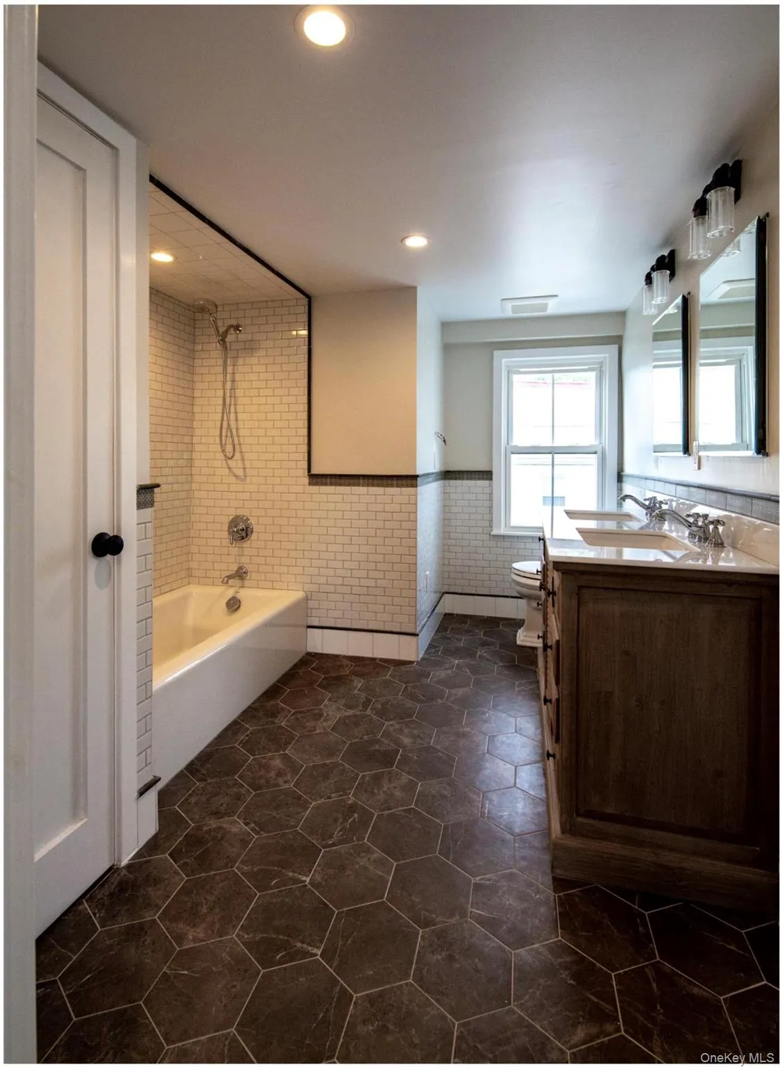 Full bathroom featuring tile walls, vanity, a wainscoted wall, shower / tub combination, and recessed lighting Full bathroom featuring tile walls, vanity, a wainscoted wall, shower / tub combination, and recessed lighting