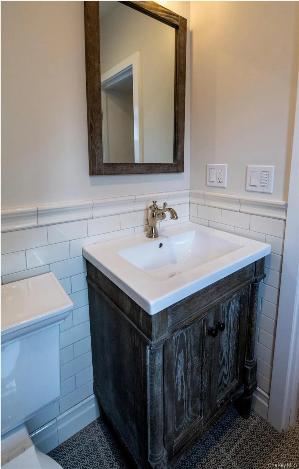 Half bathroom with tile walls, vanity, wainscoting, and tile patterned flooring Half bathroom with tile walls, vanity, wainscoting, and tile patterned flooring