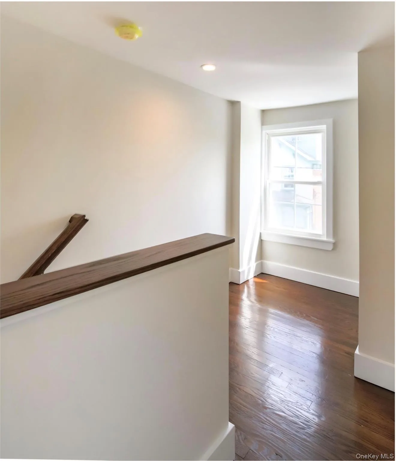 Hallway with an upstairs landing, dark wood-type flooring, and recessed lighting Hallway with an upstairs landing, dark wood-type flooring, and recessed lighting