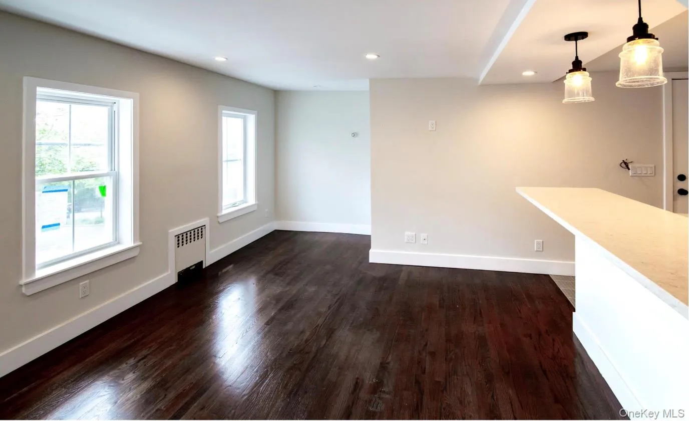 Unfurnished living room featuring radiator, dark wood-type flooring, and recessed lighting Unfurnished living room featuring radiator, dark wood-type flooring, and recessed lighting