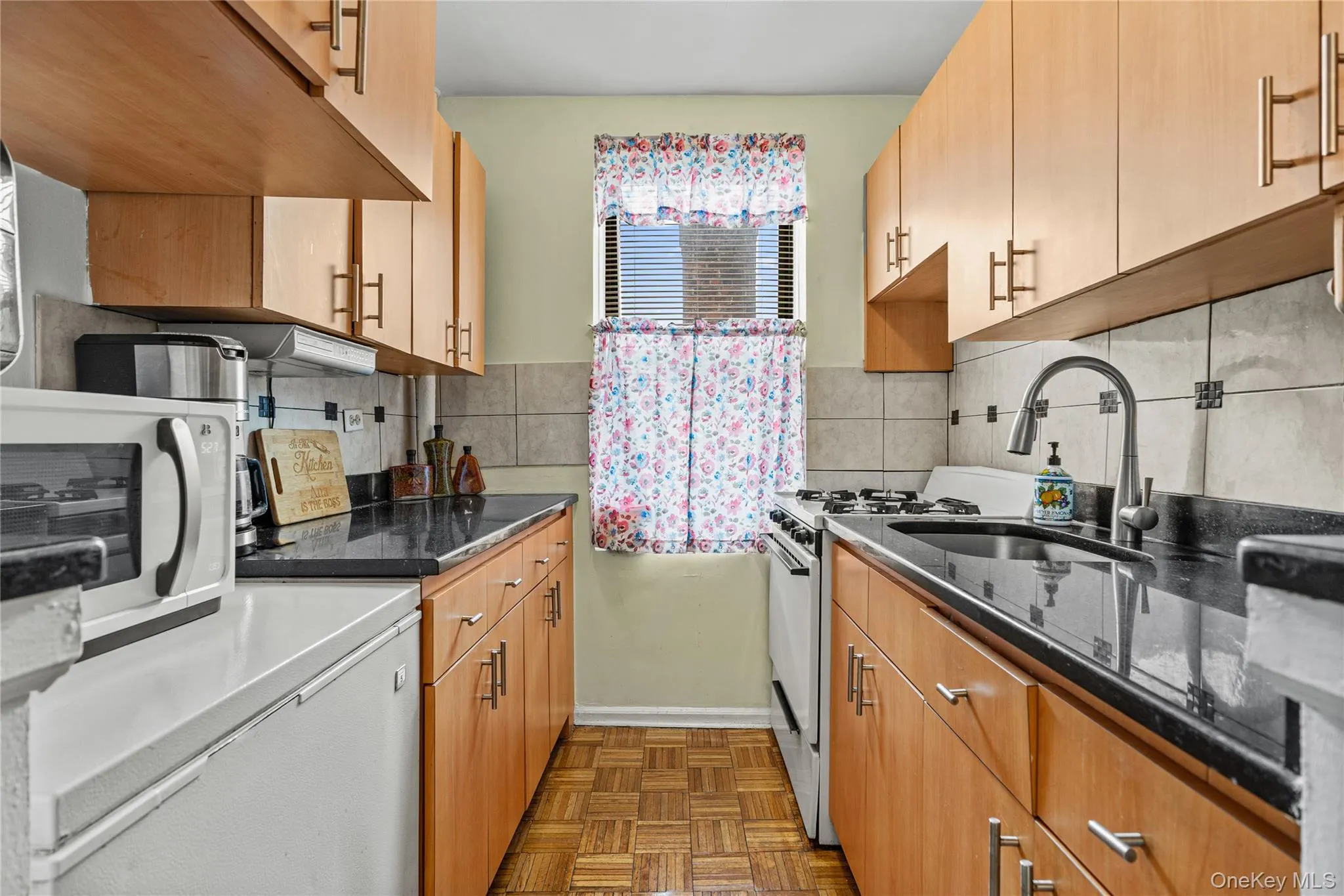 This attractive modern kitchen includes a french-door refrigerator, gas range, box freezer, washer, tile backsplash, and stone counters. This attractive modern kitchen includes a french-door refrigerator, gas range, box freezer, washer, tile backsplash, and stone counters.