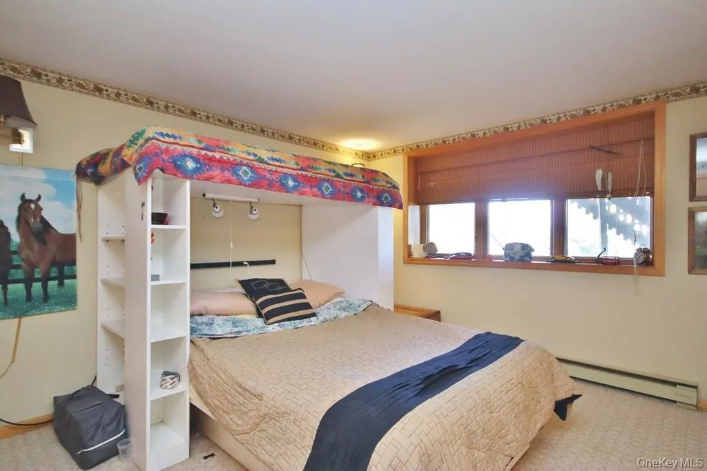 Bedroom featuring a baseboard heating unit and carpet floors Bedroom featuring a baseboard heating unit and carpet floors