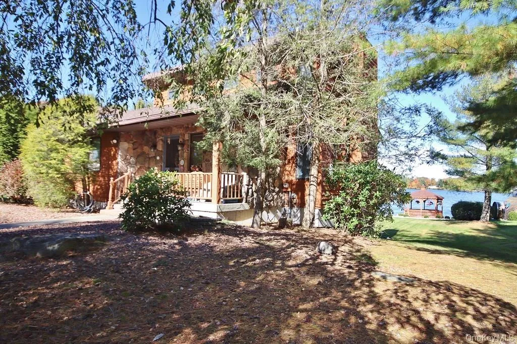 Rear view of house featuring a porch, stone siding, and a lawn Rear view of house featuring a porch, stone siding, and a lawn