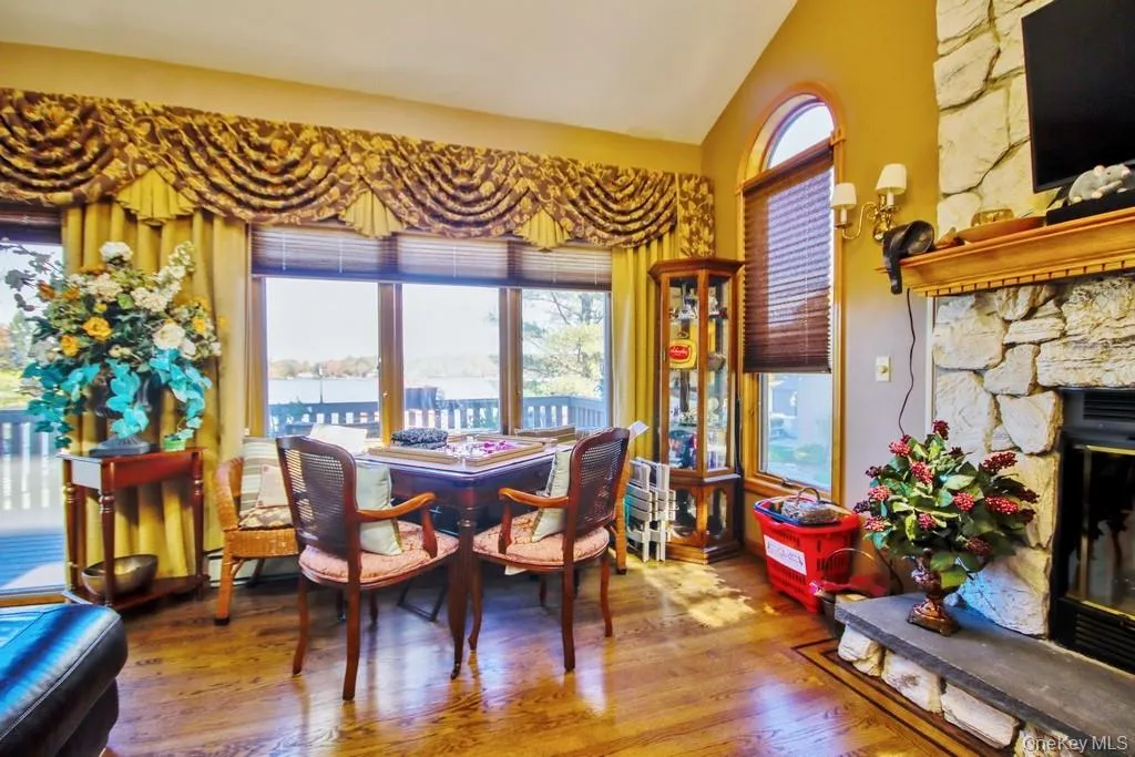 Dining space with lofted ceiling, wood finished floors, and a stone fireplace Dining space with lofted ceiling, wood finished floors, and a stone fireplace
