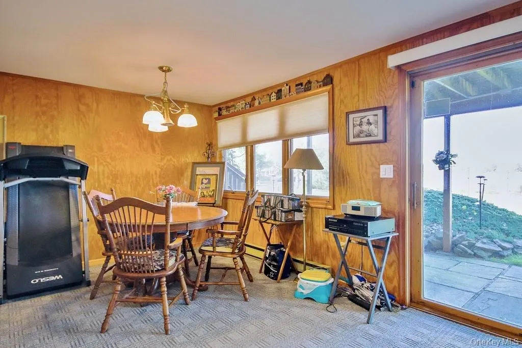 Carpeted dining room with wooden walls and a chandelier Carpeted dining room with wooden walls and a chandelier