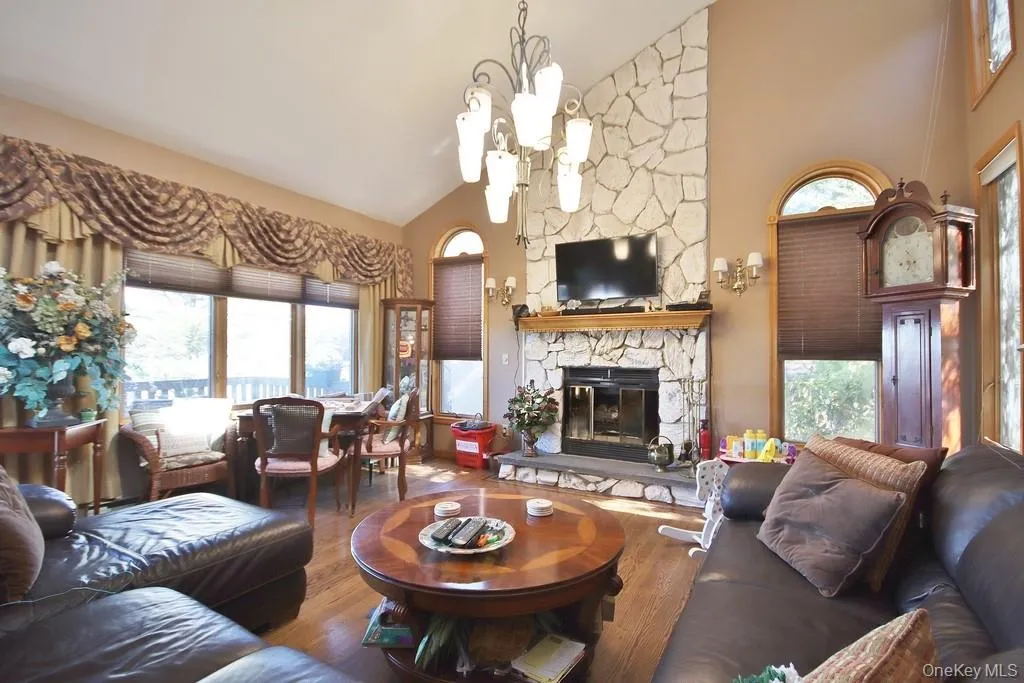 Living area featuring wood finished floors, a fireplace, healthy amount of natural light, and high vaulted ceiling Living area featuring wood finished floors, a fireplace, healthy amount of natural light, and high vaulted ceiling