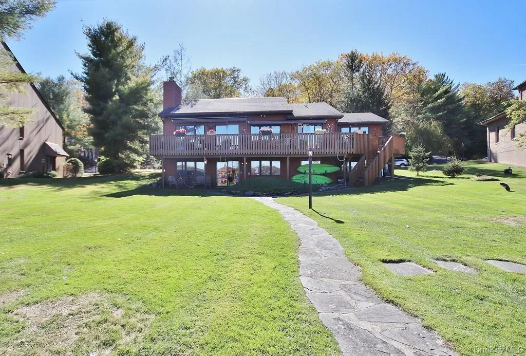 Rear view of house featuring a deck, a yard, a chimney, and stairway Rear view of house featuring a deck, a yard, a chimney, and stairway