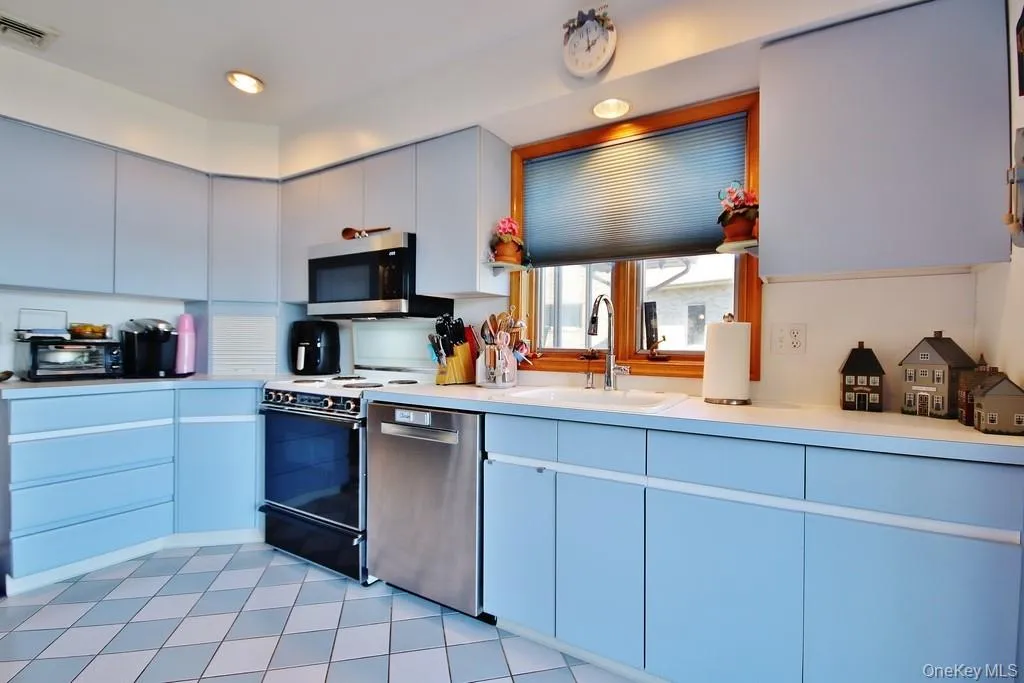 Kitchen featuring light countertops, modern cabinets, appliances with stainless steel finishes, and light tile patterned floors Kitchen featuring light countertops, modern cabinets, appliances with stainless steel finishes, and light tile patterned floors
