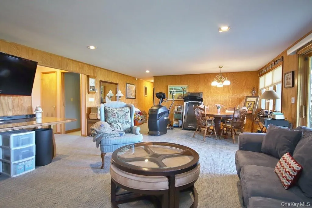 Living room with carpet floors, a chandelier, wooden walls, and recessed lighting Living room with carpet floors, a chandelier, wooden walls, and recessed lighting