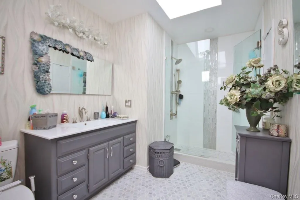 Full bath featuring a walk in shower, vanity, a skylight, and light tile patterned flooring Full bath featuring a walk in shower, vanity, a skylight, and light tile patterned flooring