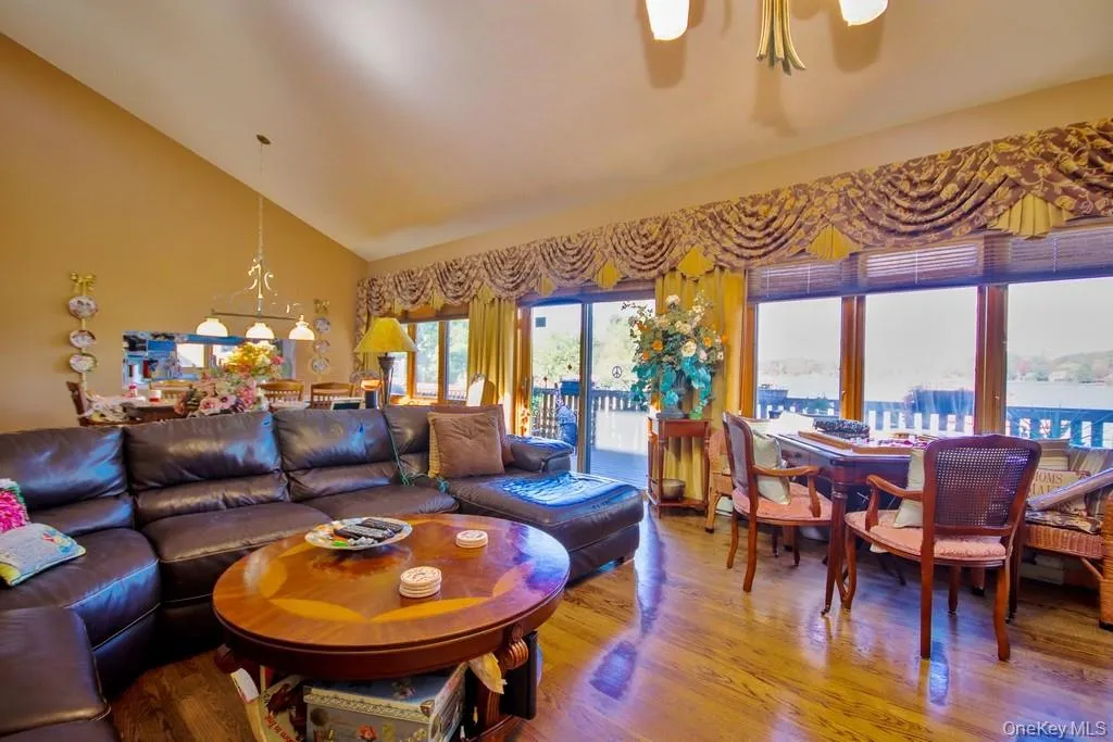 Living area with wood finished floors, high vaulted ceiling, and ceiling fan Living area with wood finished floors, high vaulted ceiling, and ceiling fan