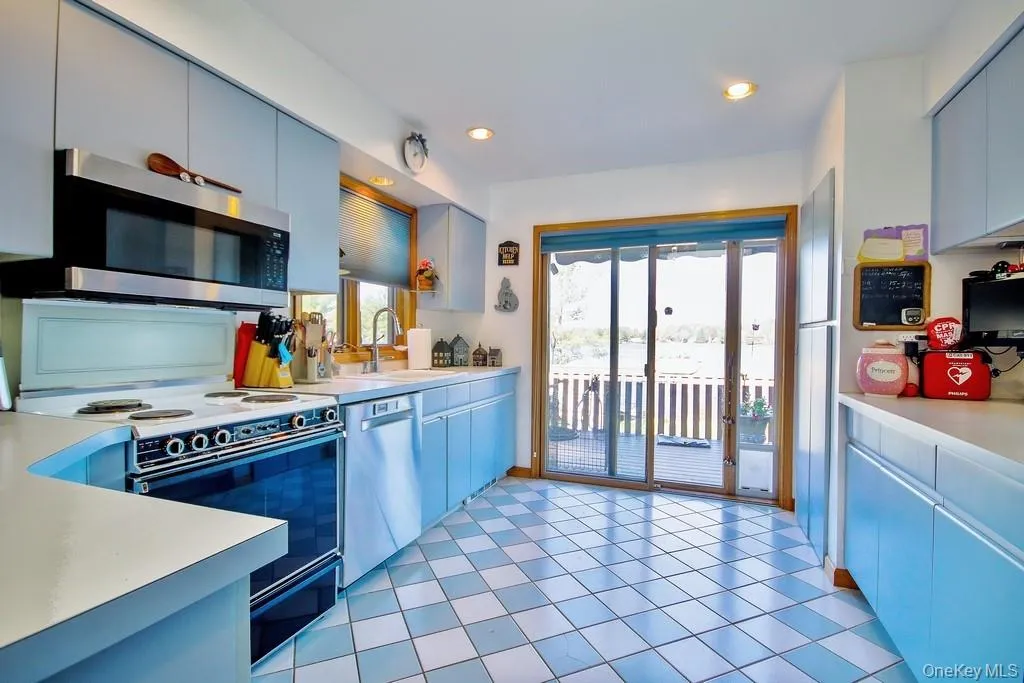 Kitchen with appliances with stainless steel finishes, light countertops, blue cabinetry, recessed lighting, and light tile patterned flooring Kitchen with appliances with stainless steel finishes, light countertops, blue cabinetry, recessed lighting, and light tile patterned flooring