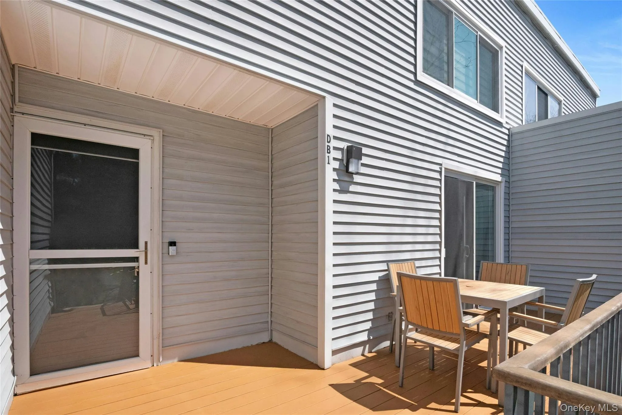 Private outdoor patio featuring a wood-finish deck and gray horizontal siding Private outdoor patio featuring a wood-finish deck and gray horizontal siding