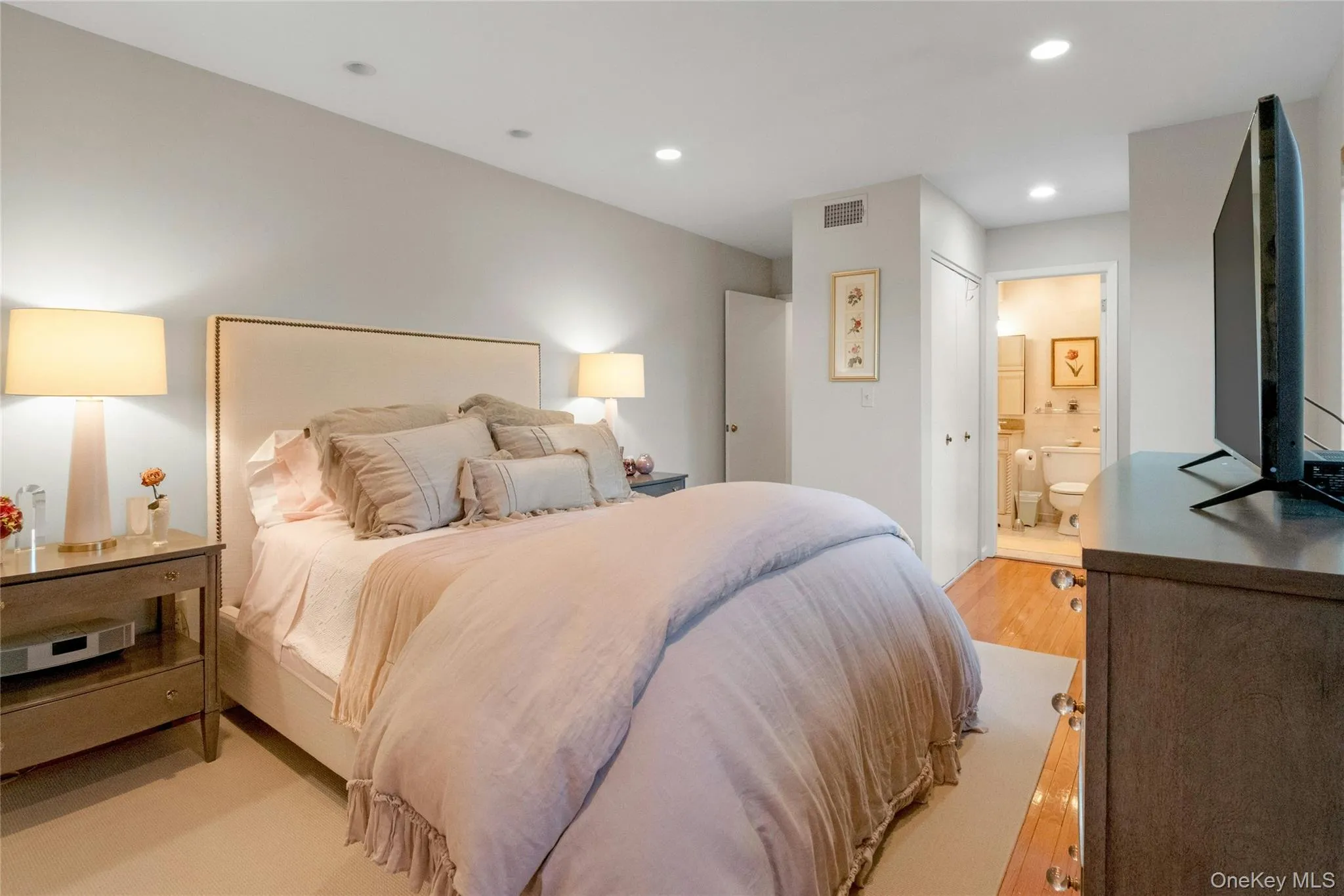 Recessed ceiling lighting illuminates a room featuring light-toned walls and hardwood flooring Recessed ceiling lighting illuminates a room featuring light-toned walls and hardwood flooring