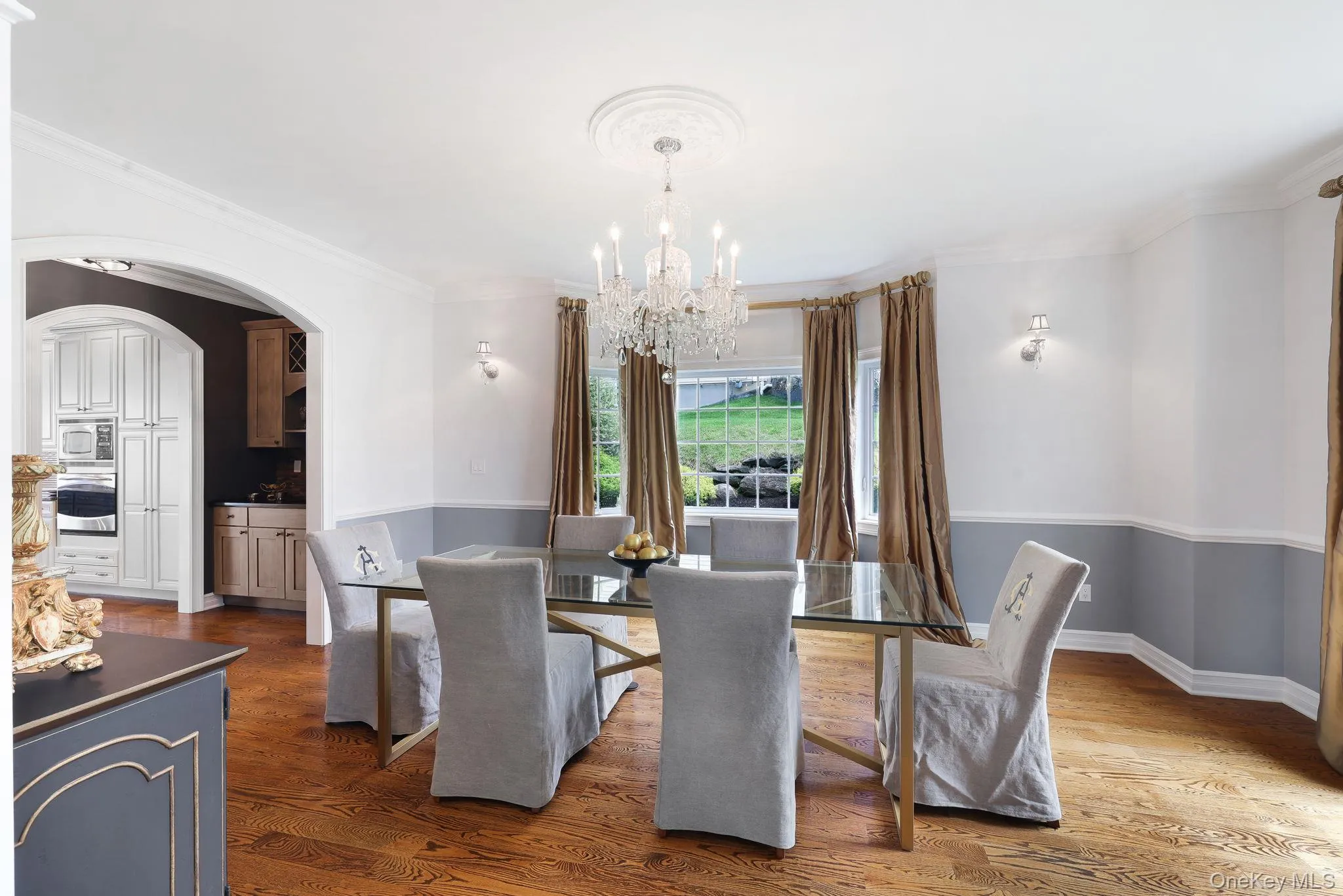 Hardwood flooring, arched doorway, built-in kitchen cabinetry, decorative ceiling medallion, and wall sconces Hardwood flooring, arched doorway, built-in kitchen cabinetry, decorative ceiling medallion, and wall sconces