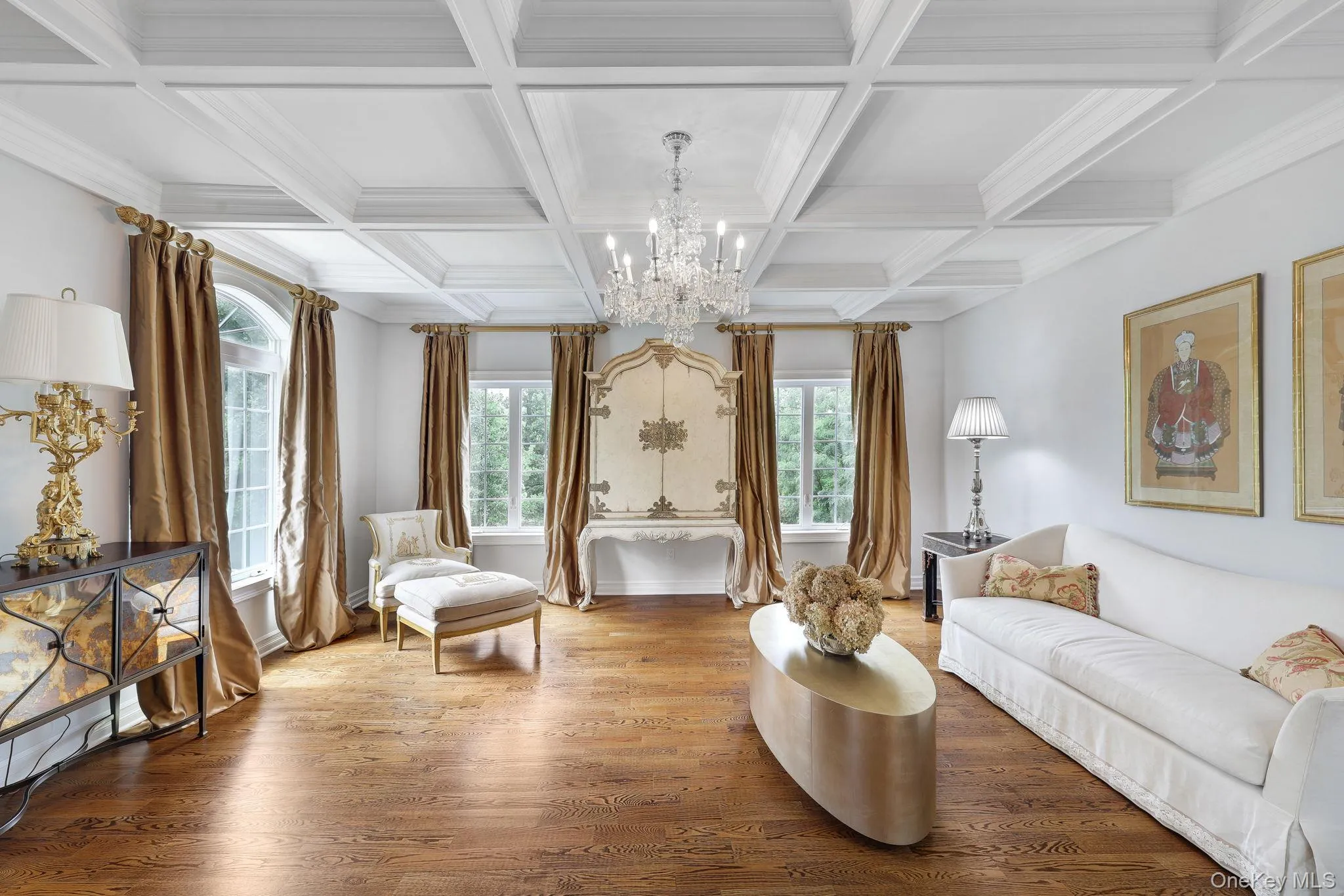 Coffered ceiling with a crystal chandelier, wood-finish flooring, and multiple windows Coffered ceiling with a crystal chandelier, wood-finish flooring, and multiple windows