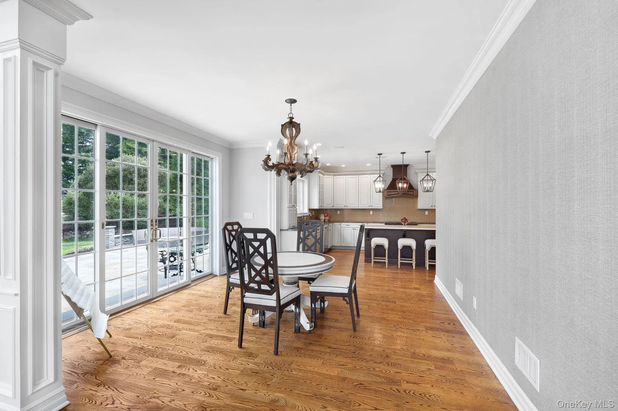Hardwood flooring, crown molding, wall paneling, French doors, and a decorative chandelier and access to outdoor patio Hardwood flooring, crown molding, wall paneling, French doors, and a decorative chandelier and access to outdoor patio