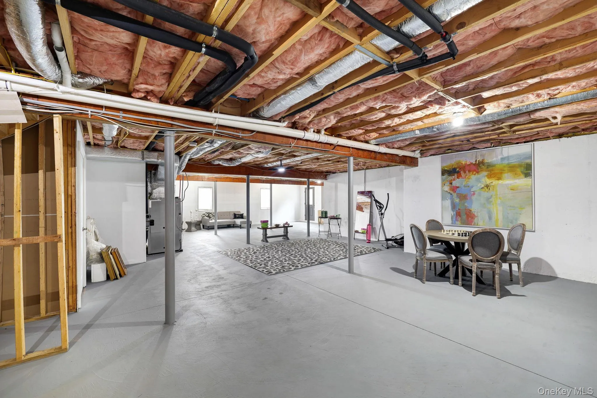 Spacious unfinished basement with exposed wooden joists, concrete flooring, and metal support columns Spacious unfinished basement with exposed wooden joists, concrete flooring, and metal support columns