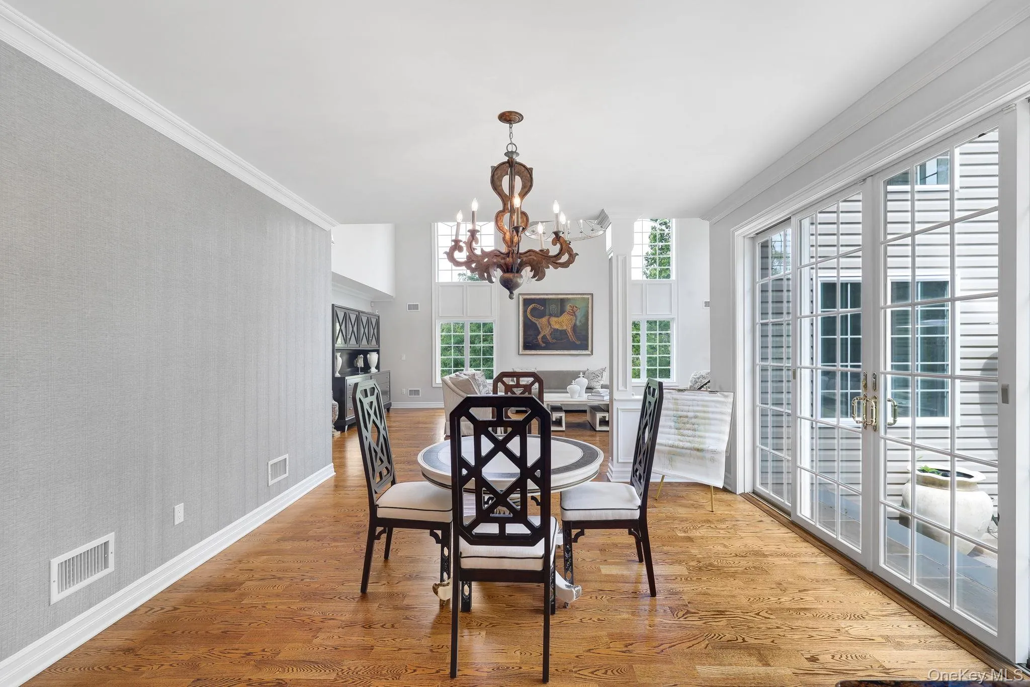 Hardwood flooring throughout, elegant crown molding, double French doors with transom windows, and a chandelier light fixture and access to outdoor patio Hardwood flooring throughout, elegant crown molding, double French doors with transom windows, and a chandelier light fixture and access to outdoor patio