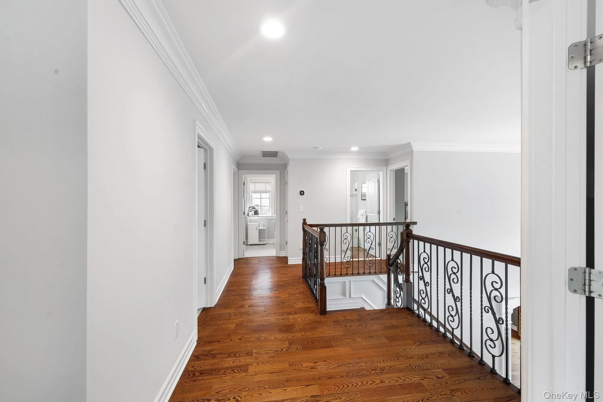 Hardwood flooring, crown molding, recessed lighting, white walls, and wrought iron railing overlooks great room Hardwood flooring, crown molding, recessed lighting, white walls, and wrought iron railing overlooks great room
