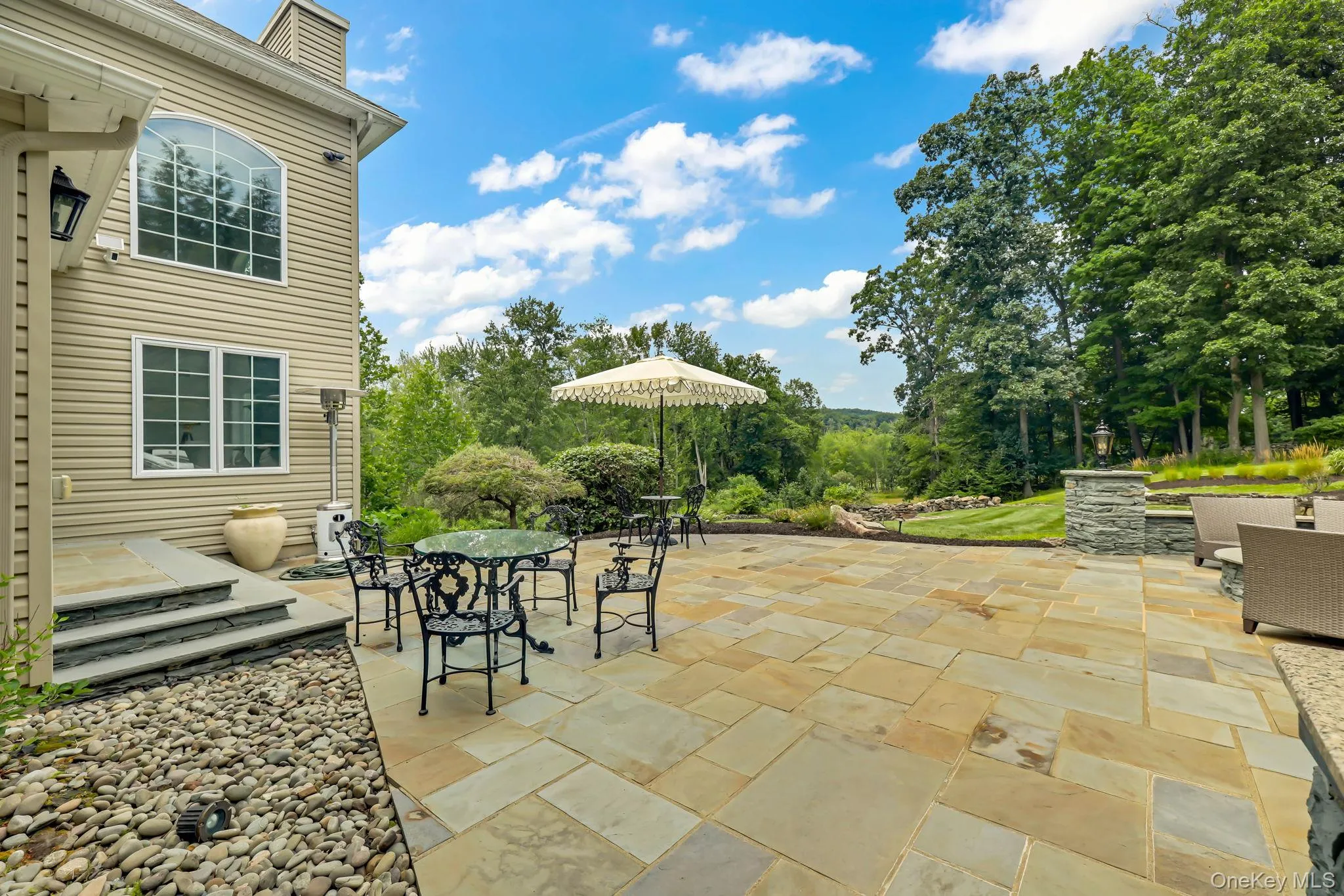 Expansive paver patio with stone retaining walls, stone steps, and a large arched window Expansive paver patio with stone retaining walls, stone steps, and a large arched window