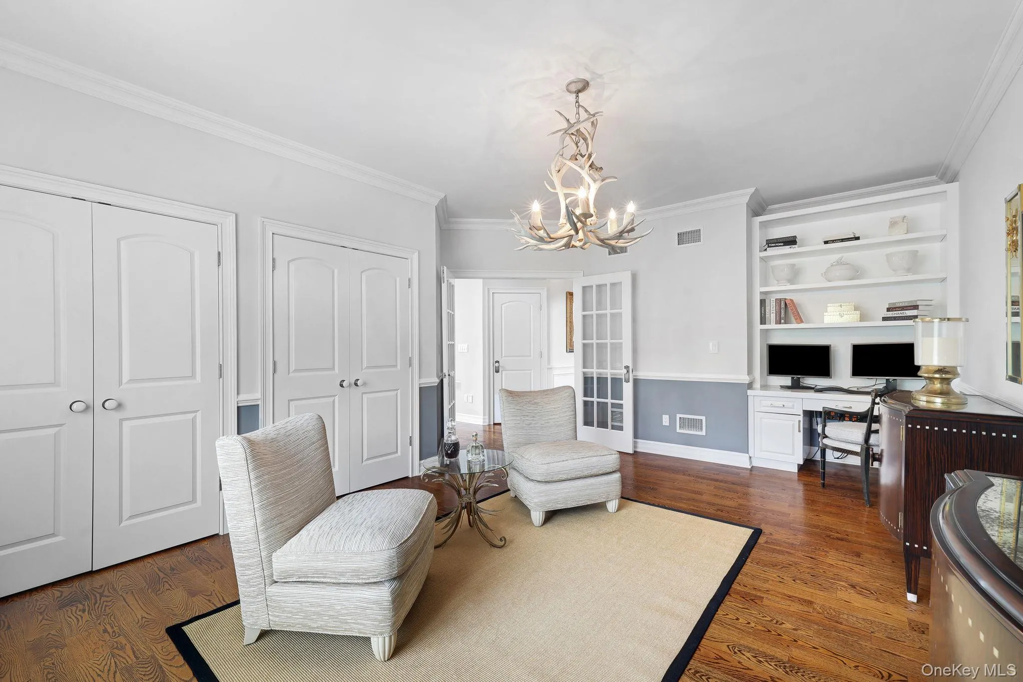 Hardwood flooring, custom built-in shelving, crown molding, double doors, and a decorative antler chandelier Hardwood flooring, custom built-in shelving, crown molding, double doors, and a decorative antler chandelier
