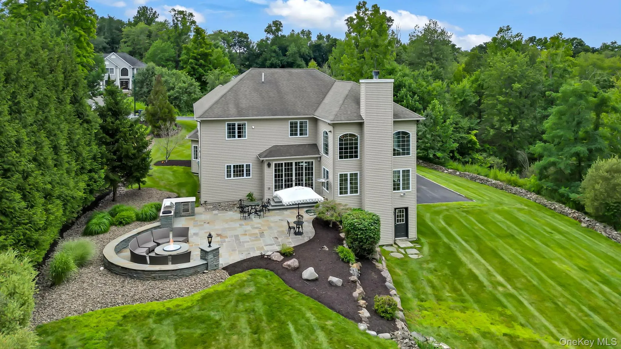Expansive stone patio with built-in seating area and fire pit and extensive backyard. Expansive stone patio with built-in seating area and fire pit and extensive backyard.