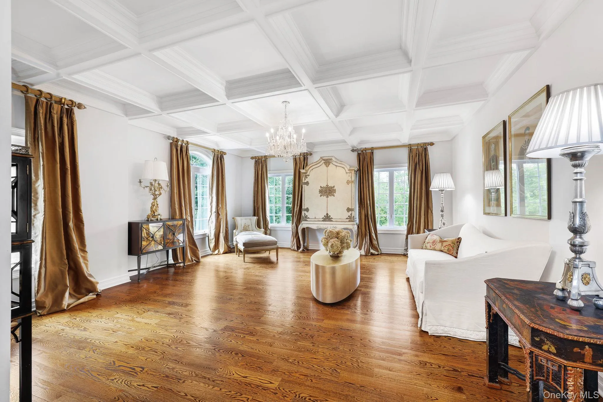 Coffered ceiling with a crystal chandelier, wood-finish flooring, and multiple windows Coffered ceiling with a crystal chandelier, wood-finish flooring, and multiple windows