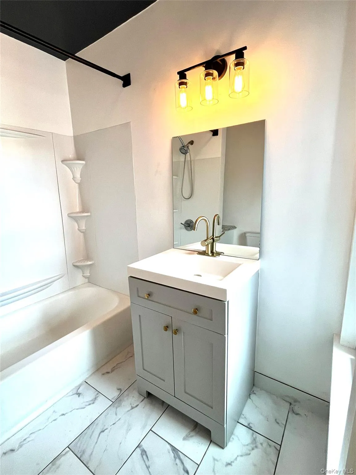 Bathroom featuring a modern vanity with light grey cabinetry and gold-tone hardware, a rectangular sink, and a gold-tone faucet Bathroom featuring a modern vanity with light grey cabinetry and gold-tone hardware, a rectangular sink, and a gold-tone faucet