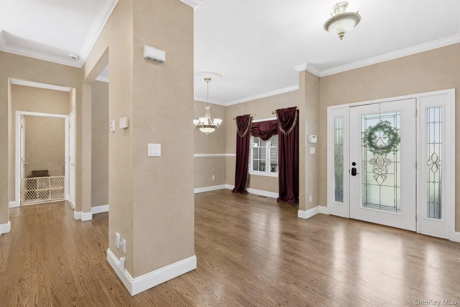 Inviting entry hall with hardwood floors, crown molding, and a chandelier Inviting entry hall with hardwood floors, crown molding, and a chandelier