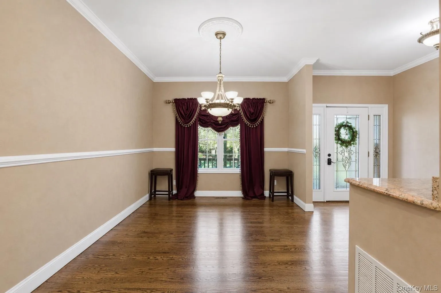 Formal Dining room features rich hardwood flooring, neutral-toned walls with chair rail and crown molding, and a prominent window Formal Dining room features rich hardwood flooring, neutral-toned walls with chair rail and crown molding, and a prominent window
