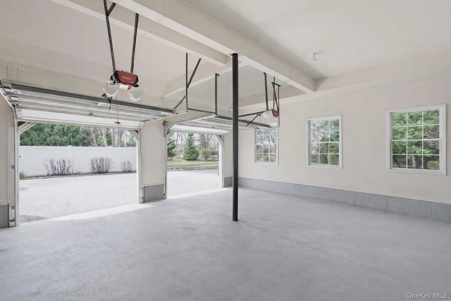 Spacious garage featuring two garage doors, three windows, and a concrete floor Spacious garage featuring two garage doors, three windows, and a concrete floor