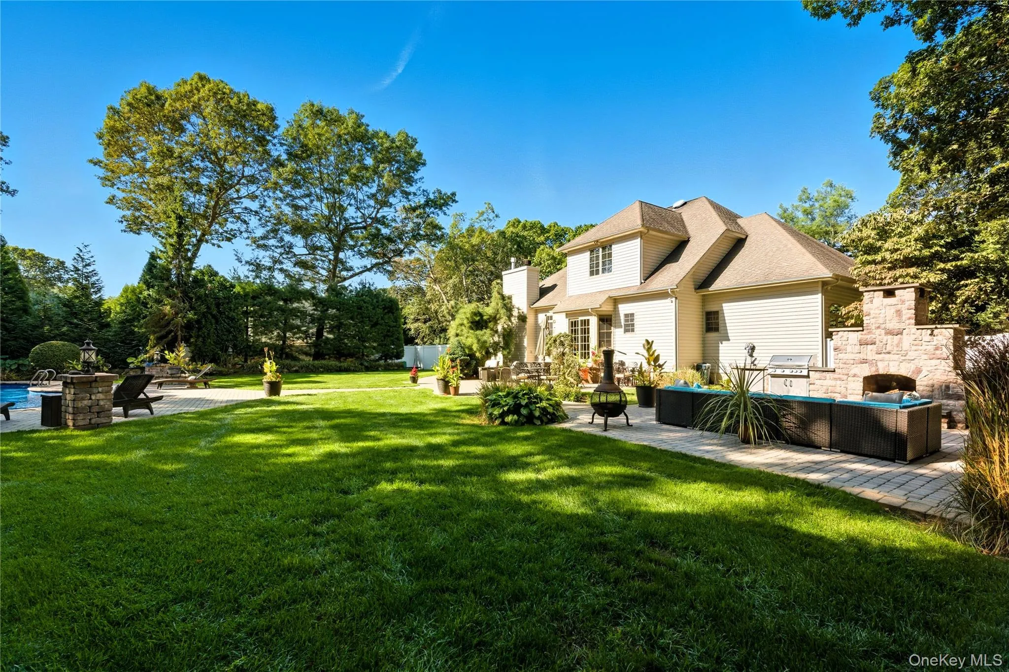 Back of property featuring a patio area, an outdoor living space with a fireplace, a lawn, and an outdoor pool Back of property featuring a patio area, an outdoor living space with a fireplace, a lawn, and an outdoor pool