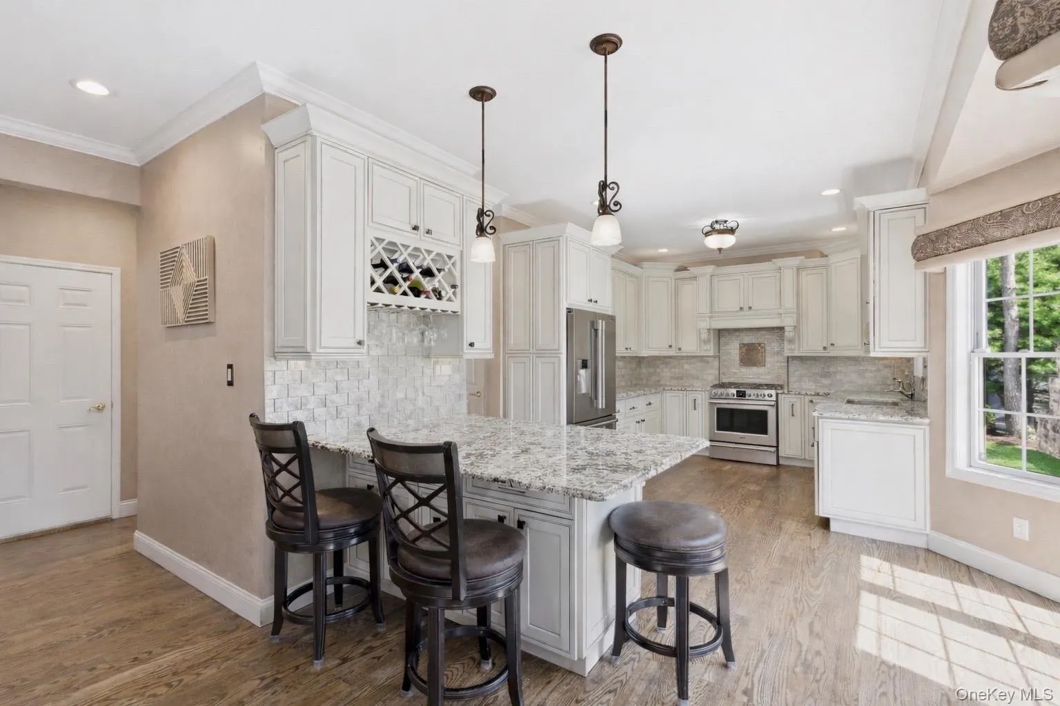 The kitchen features light-toned wooden flooring, white cabinetry, and granite countertops The kitchen features light-toned wooden flooring, white cabinetry, and granite countertops