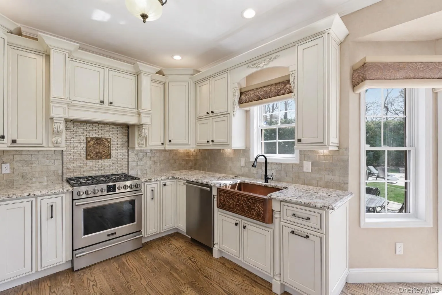 The kitchen features white cabinetry, granite countertops, a tile backsplash, and hardwood flooring The kitchen features white cabinetry, granite countertops, a tile backsplash, and hardwood flooring