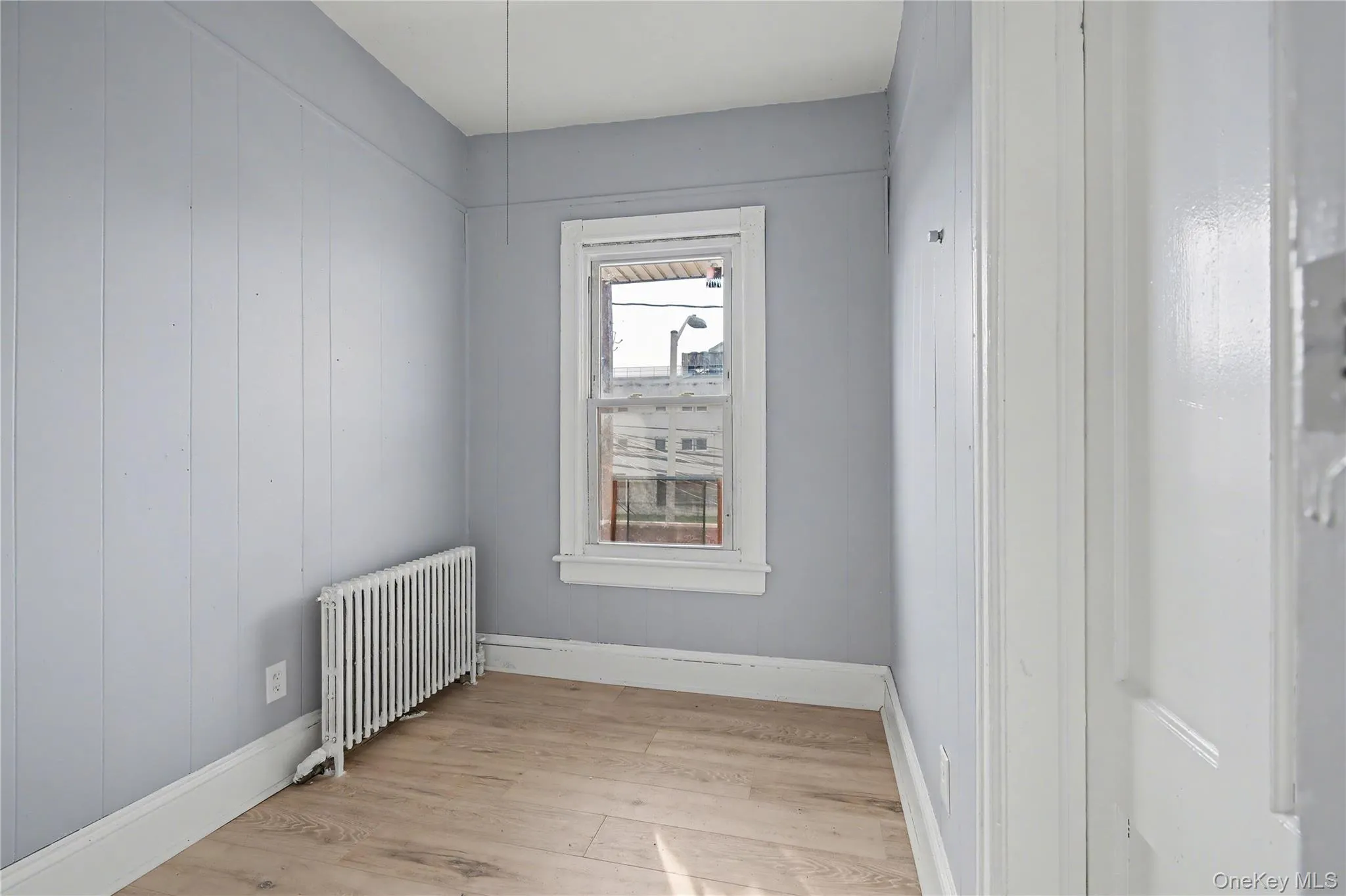 Empty room featuring radiator and light wood-style floors Empty room featuring radiator and light wood-style floors