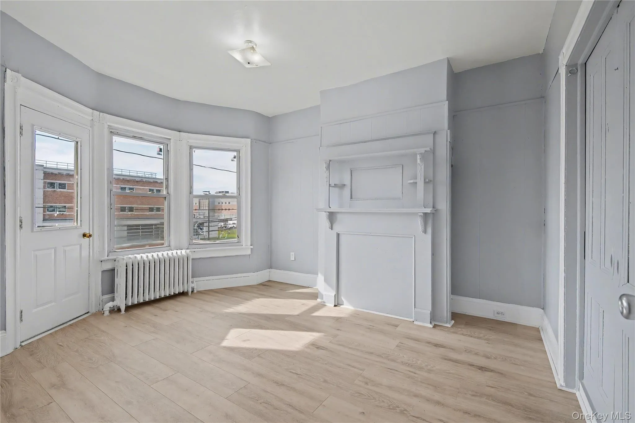 Unfurnished room with radiator heating unit and light wood-style floors Unfurnished room with radiator heating unit and light wood-style floors