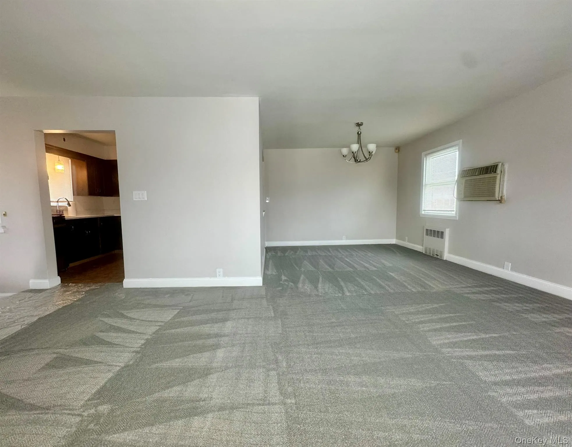 Dining room with gray carpet, suspended lighting, and radiator Dining room with gray carpet, suspended lighting, and radiator