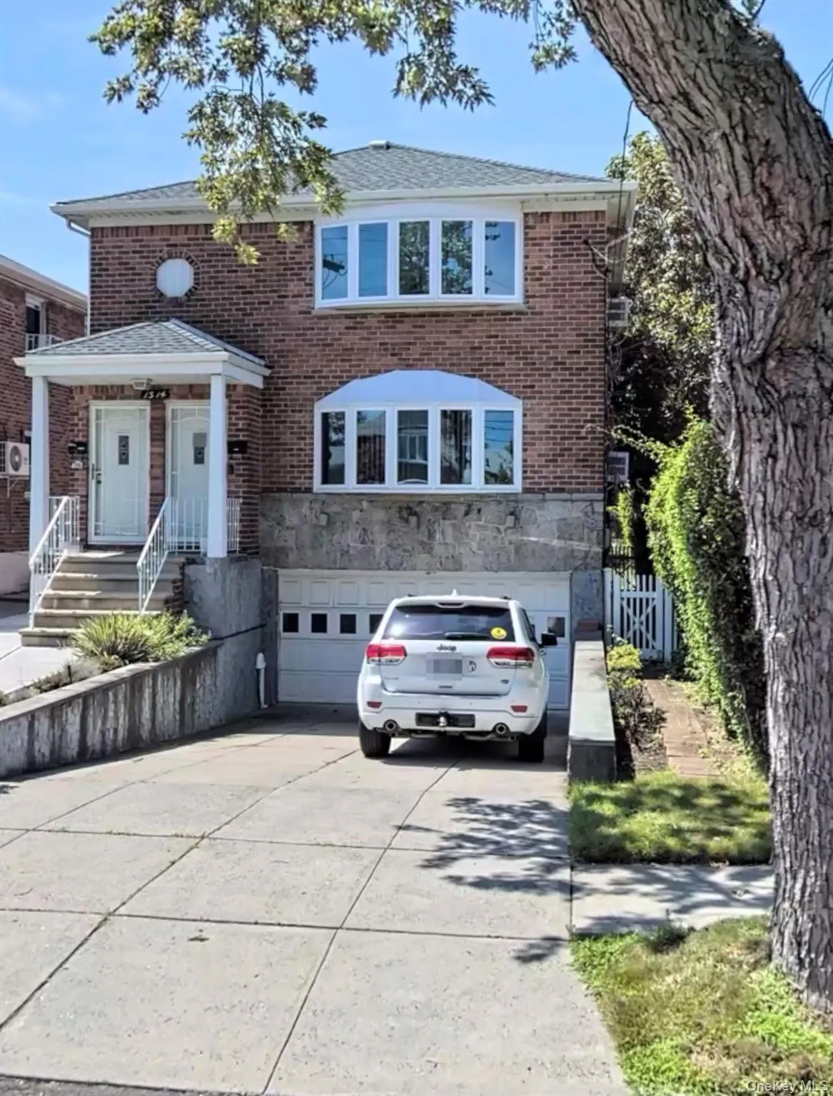 View of front facade with a garage, driveway, brick siding, and stone siding View of front facade with a garage, driveway, brick siding, and stone siding