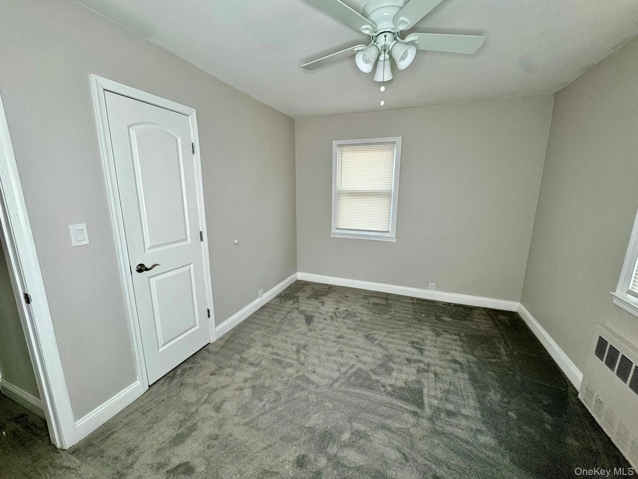 room featuring carpet, a ceiling fan, and radiator room featuring carpet, a ceiling fan, and radiator
