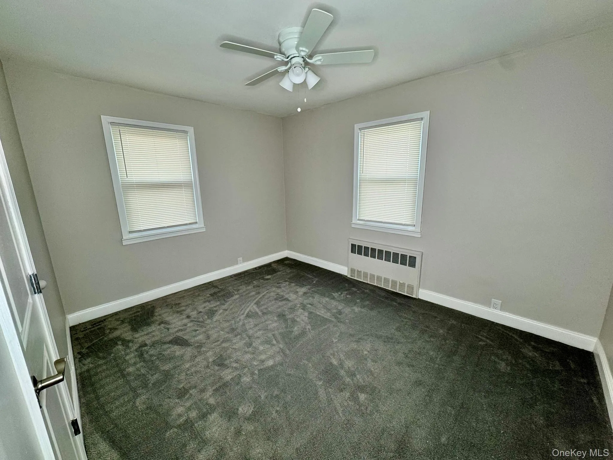 room featuring gray colored carpet, radiator heating unit, and ceiling fan room featuring gray colored carpet, radiator heating unit, and ceiling fan