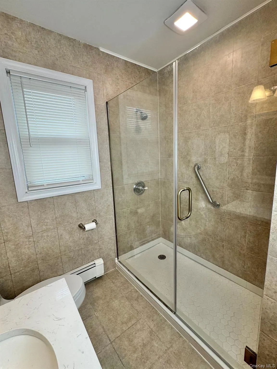 Bathroom with a shower stall, vanity, light tile patterned floors, and tile walls Bathroom with a shower stall, vanity, light tile patterned floors, and tile walls