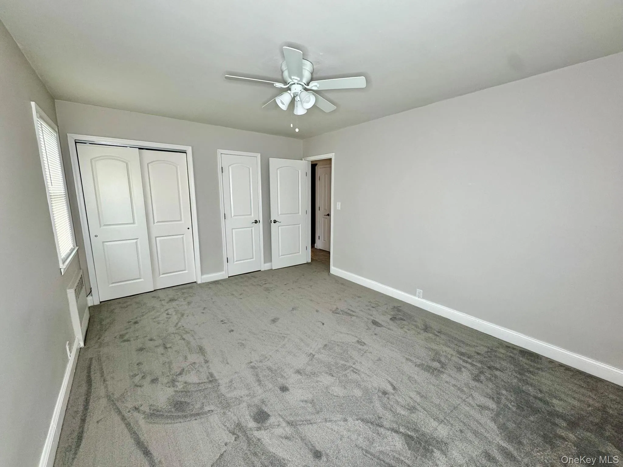 Unfurnished bedroom with a ceiling fan, 2 closet, and light colored carpet Unfurnished bedroom with a ceiling fan, 2 closet, and light colored carpet
