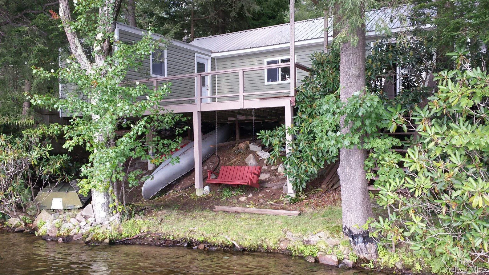 Back of property with a deck with water view and a metal roof Back of property with a deck with water view and a metal roof