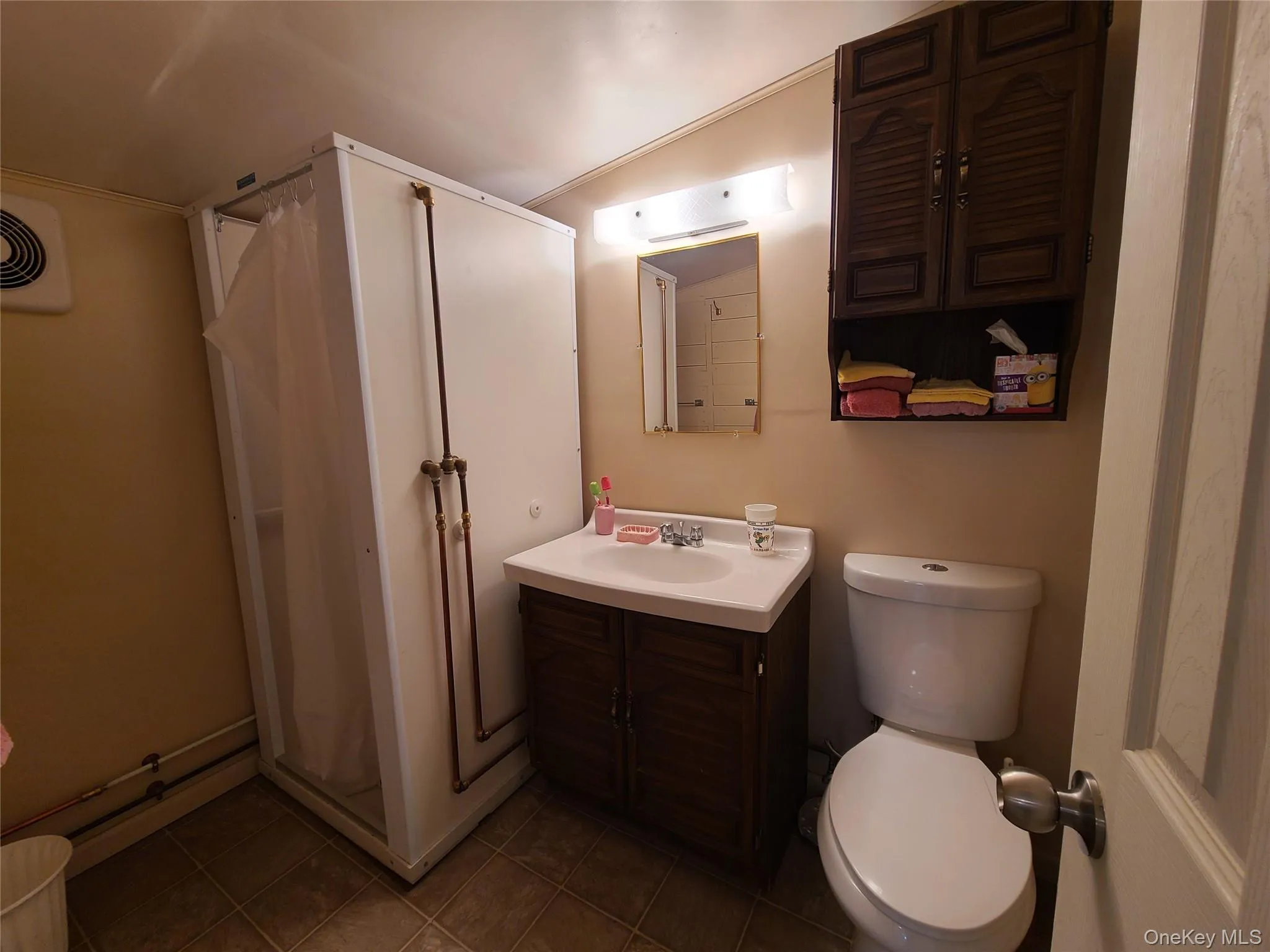 Full bathroom with vanity, a stall shower, dark tile patterned flooring, and crown molding Full bathroom with vanity, a stall shower, dark tile patterned flooring, and crown molding