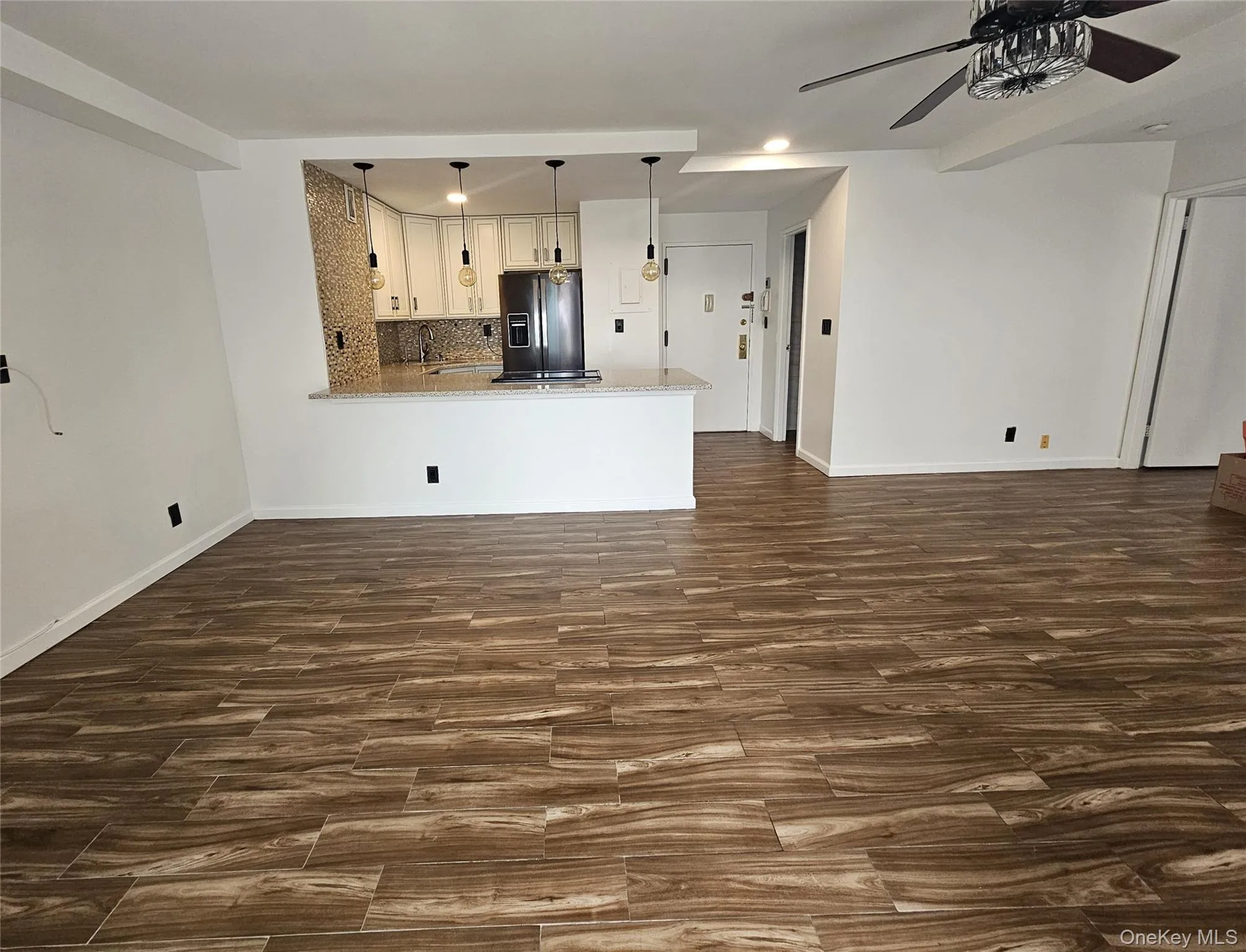 Living area featuring dark porcelain tile finished floors, an AC wall unit, and recessed lighting Living area featuring dark porcelain tile finished floors, an AC wall unit, and recessed lighting